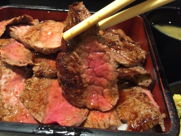 ステーキ重のお肉を箸で持ち上げている様子